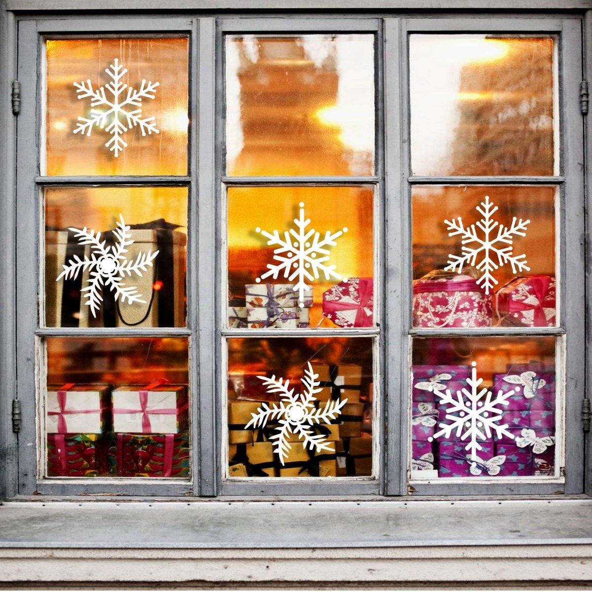 Festive window adorned with white snowflake stickers and colorful Christmas presents inside.