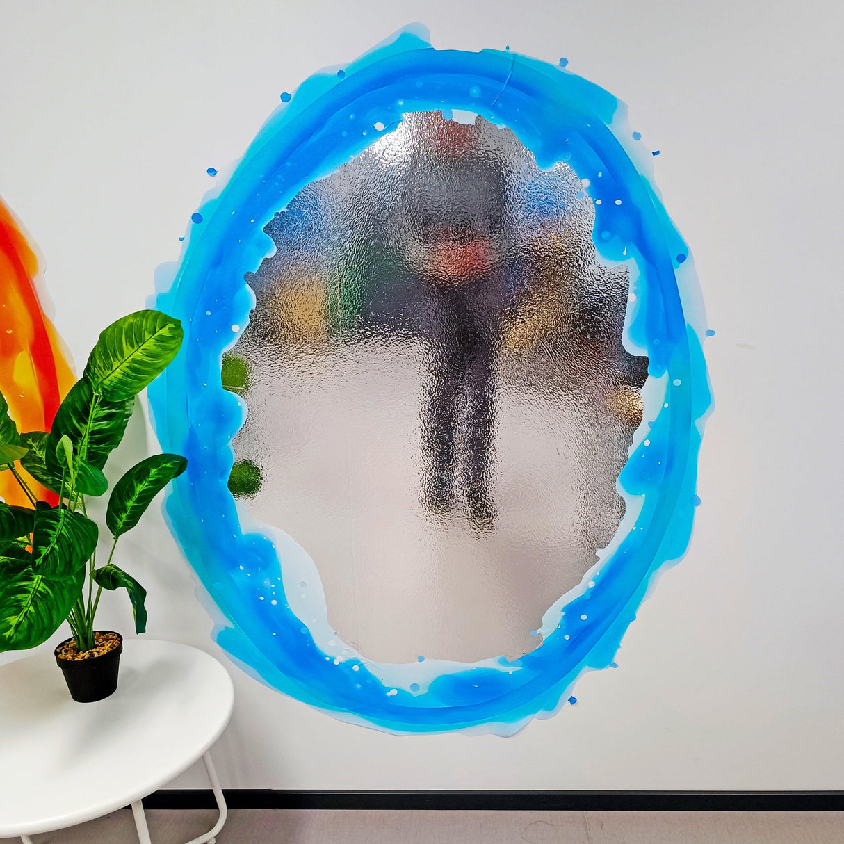 Vibrant blue and orange portal aura wall sticker with silver chrome mirror effect on a wall in a stylish room.