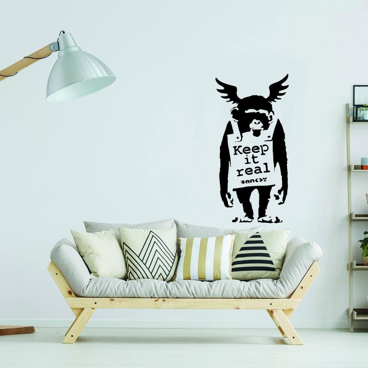 Banksy monkey graffiti decal on wall above modern sofa with cushions; urban expression wall art sticker.