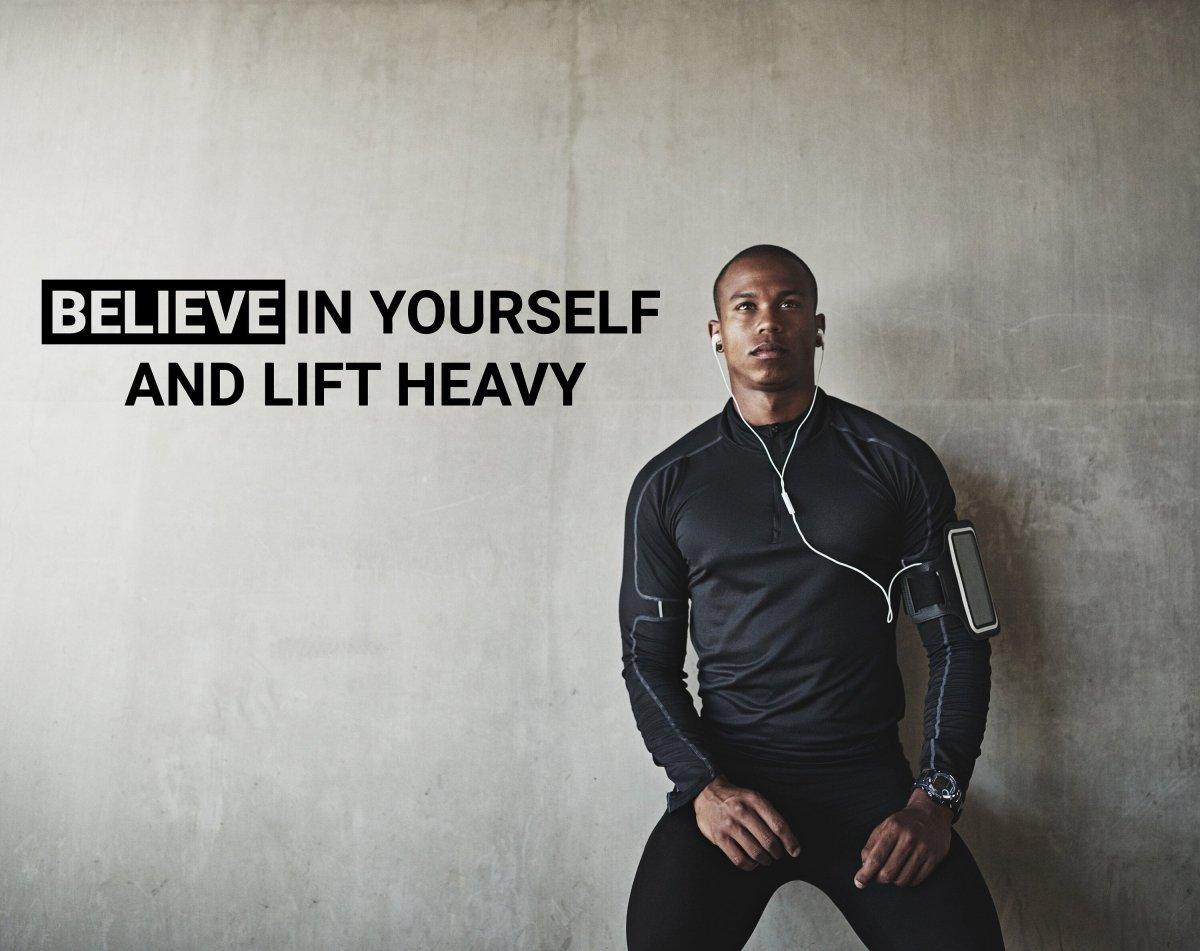 Motivational gym wall decal with the quote 'Believe in Yourself and Lift Heavy' on a fitness enthusiast.