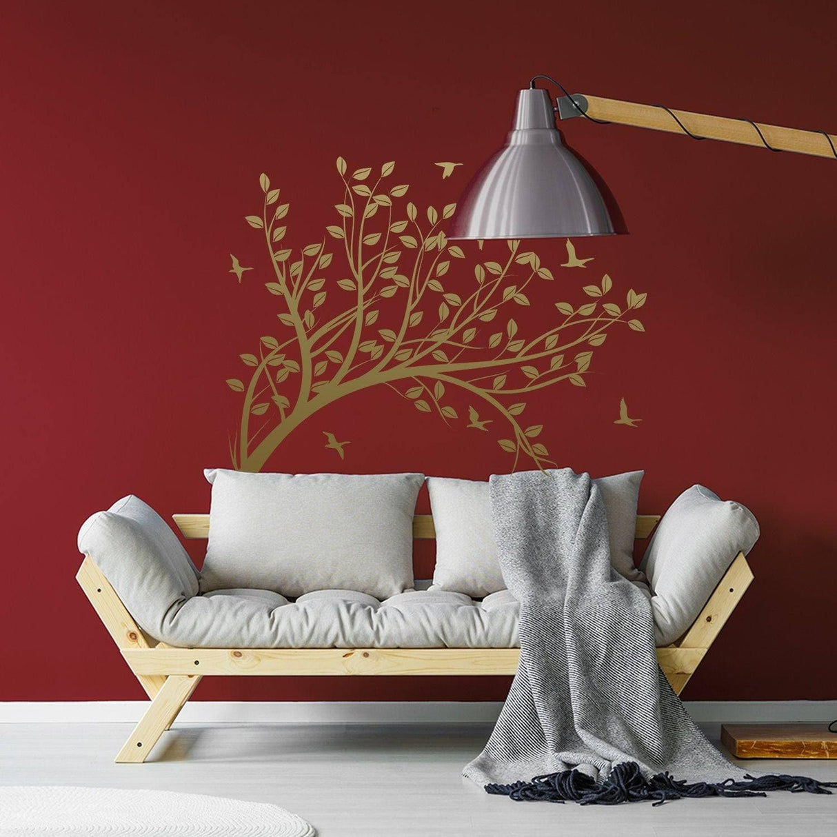 Abstract tree branch wall sticker on red wall above cozy white sofa with gray throw, adding artistic decor.