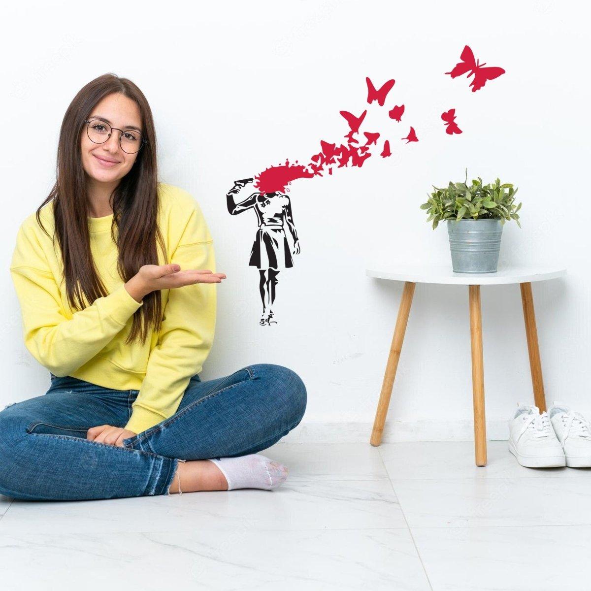 Girl sitting beside a wall featuring a butterfly vinyl sticker, showcasing emotional street art design.