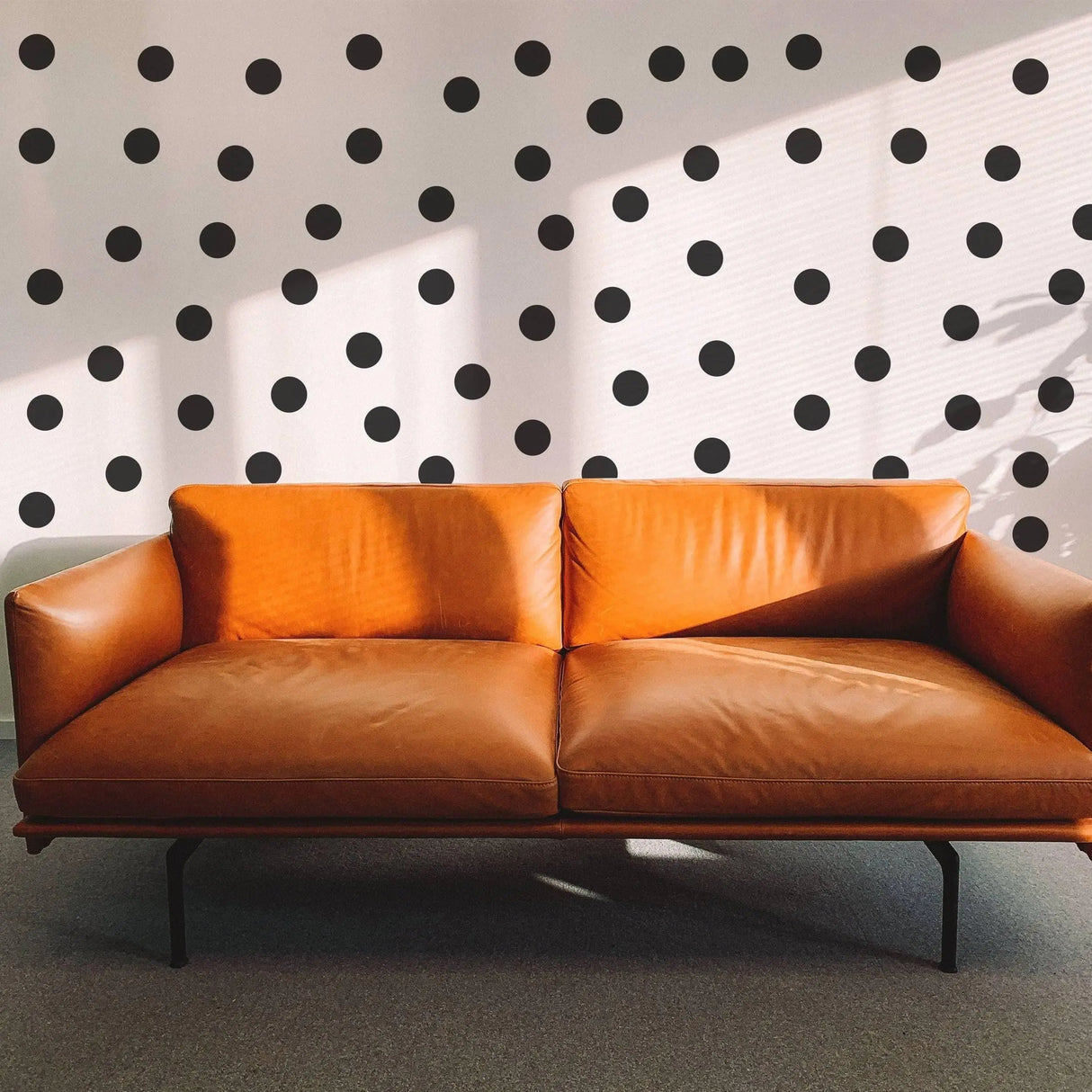 Stylish brown leather sofa in front of a wall adorned with black circle wall stickers.