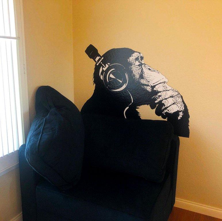 Contemplative chimp vinyl wall art decal with headphones, adding style to a cozy living space.