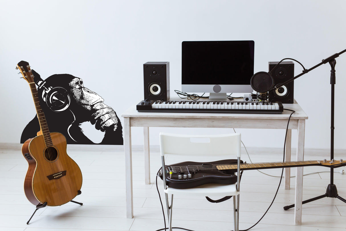 Vinyl wall art decal of a contemplative monkey with headphones in a musical workspace setting.
