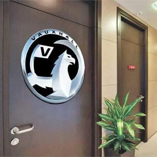 Personalized Vauxhall logo decal on a wooden office door with a potted plant beside it.