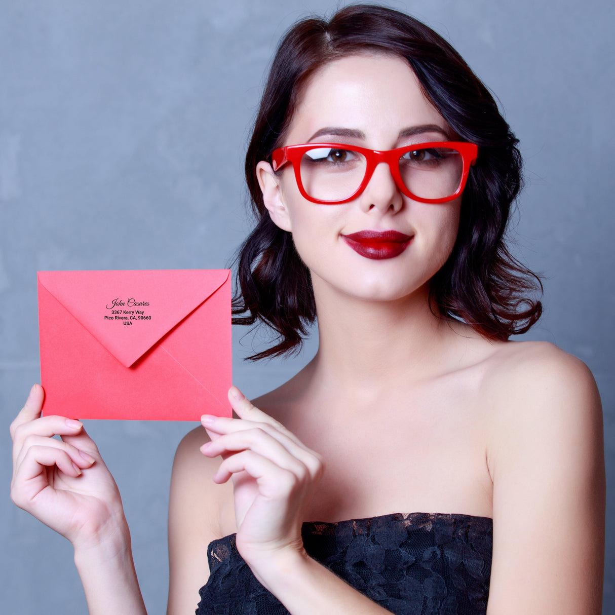 Woman holding a red envelope with custom mailing label, showcasing clear address labels in a stylish setting.
