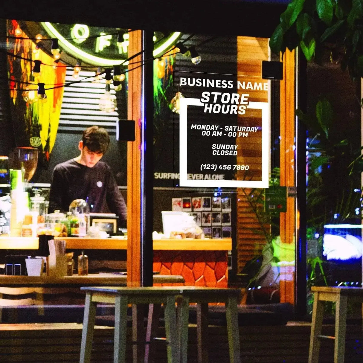 Personalized business hours decal displayed in store window with staff member working inside.