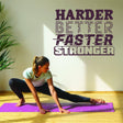 Woman doing yoga on a purple mat beneath a motivational wall decal: 'Harder, Better, Faster, Stronger'.