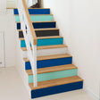 Gradient color stair riser decals in blue and teal on wooden stairs, adding vibrant style and personality to the staircase.