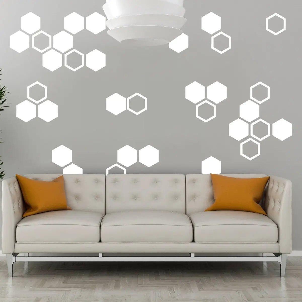 Hexagon glow in the dark wall stickers on a gray wall above a modern sofa with orange cushions.