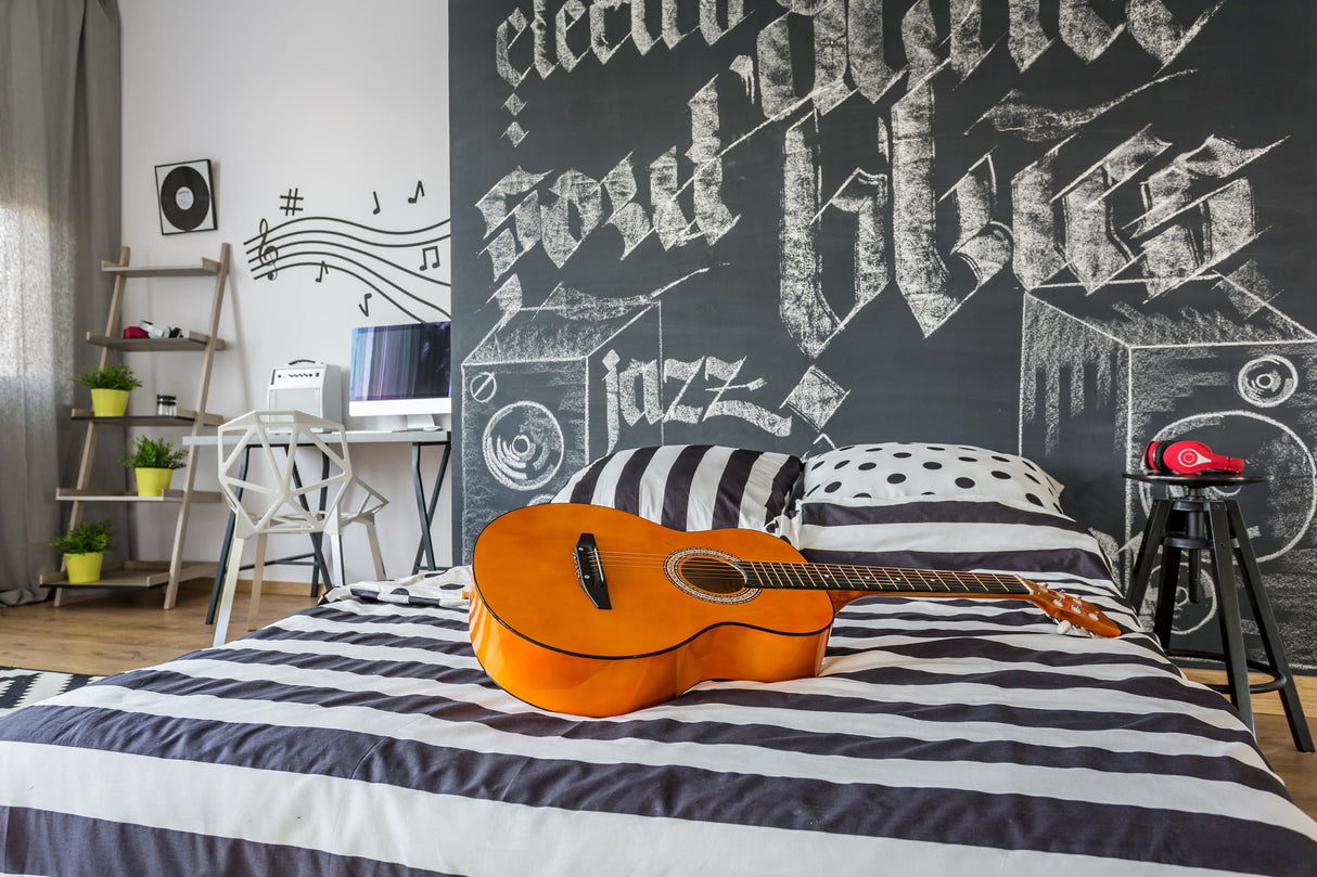 Cozy bedroom with striped bedding, an acoustic guitar on the bed, and a musical chalkboard wall decor.