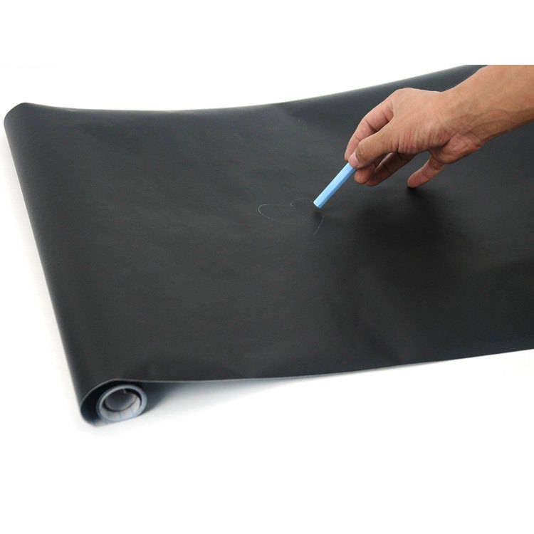 Hand writing on a peel-and-stick chalkboard wall decal with chalk, showcasing its writable surface.