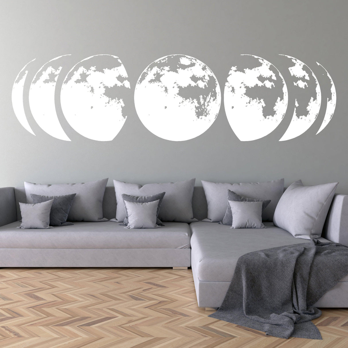 Moon phase wall stickers on a smooth wall above a modern gray sofa.