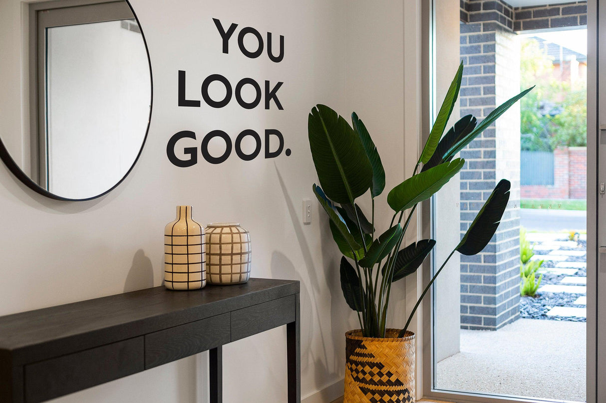 Uplifting 'You Look Good' mirror decal displayed in a stylish entryway with plants and decorative vases.