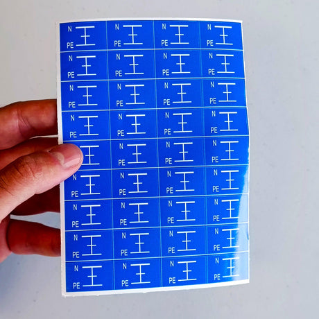 Blue electrical component labels showing Neutral (N) and Protective Earth (PE) symbols on a sticker sheet.