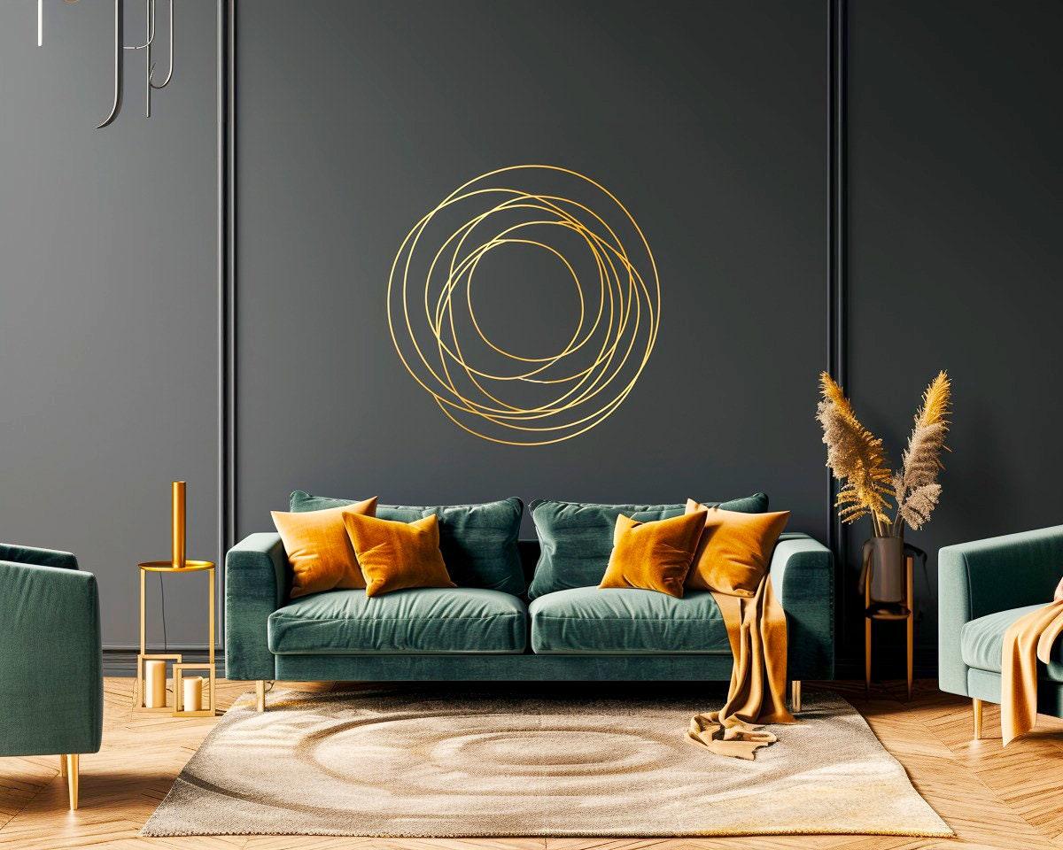 Elegant gold circle wall sticker on dark wall above teal sofa with orange cushions in modern living room decor.