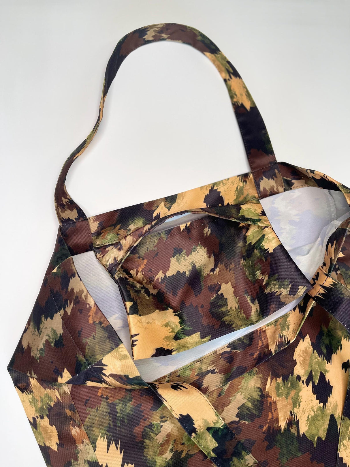 Close-up of a women's black shopper bag with military brown patterns and straps.