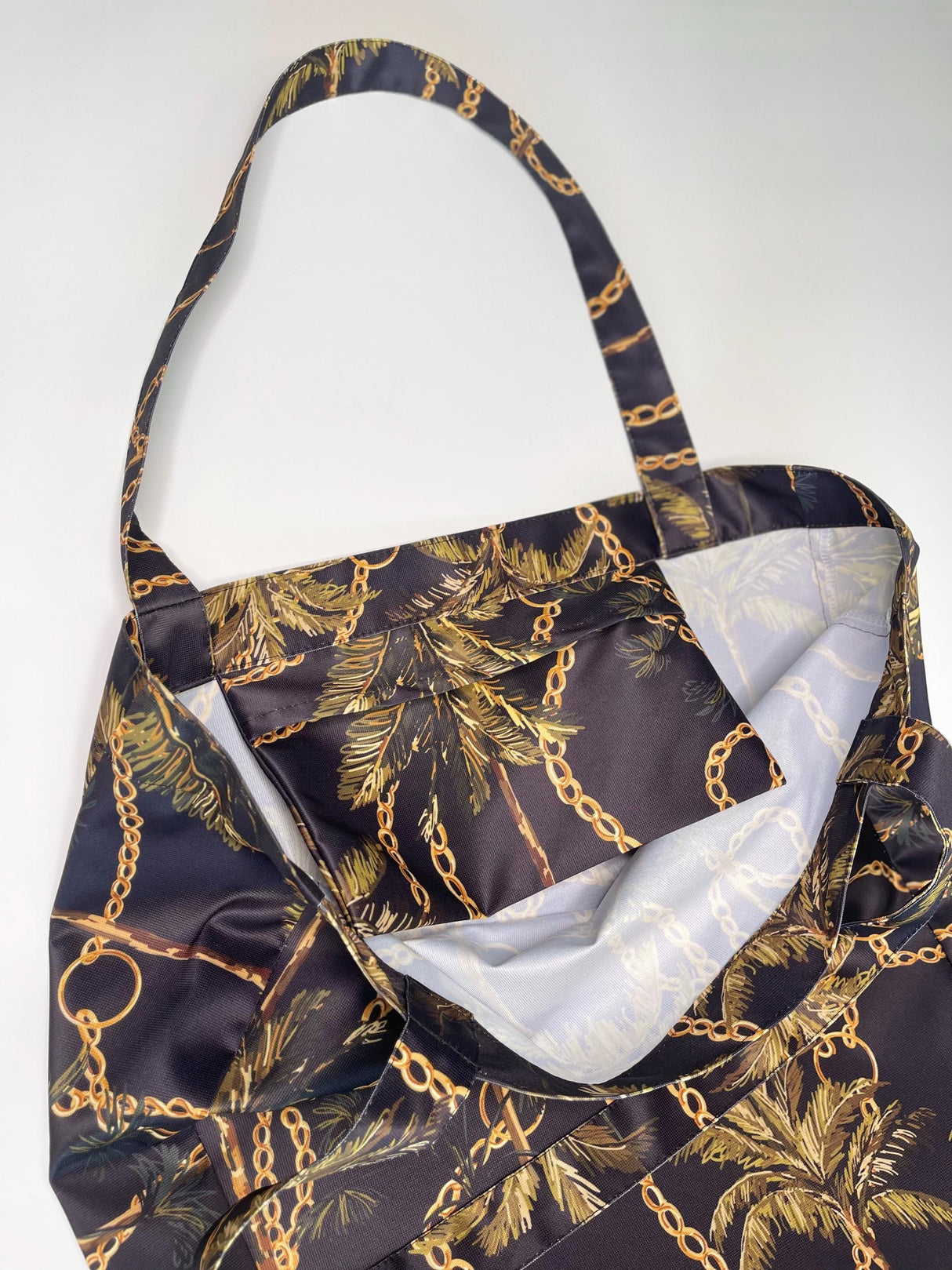Close-up of a women's black shopper bag with palm and chain patterns, showcasing its stylish interior.