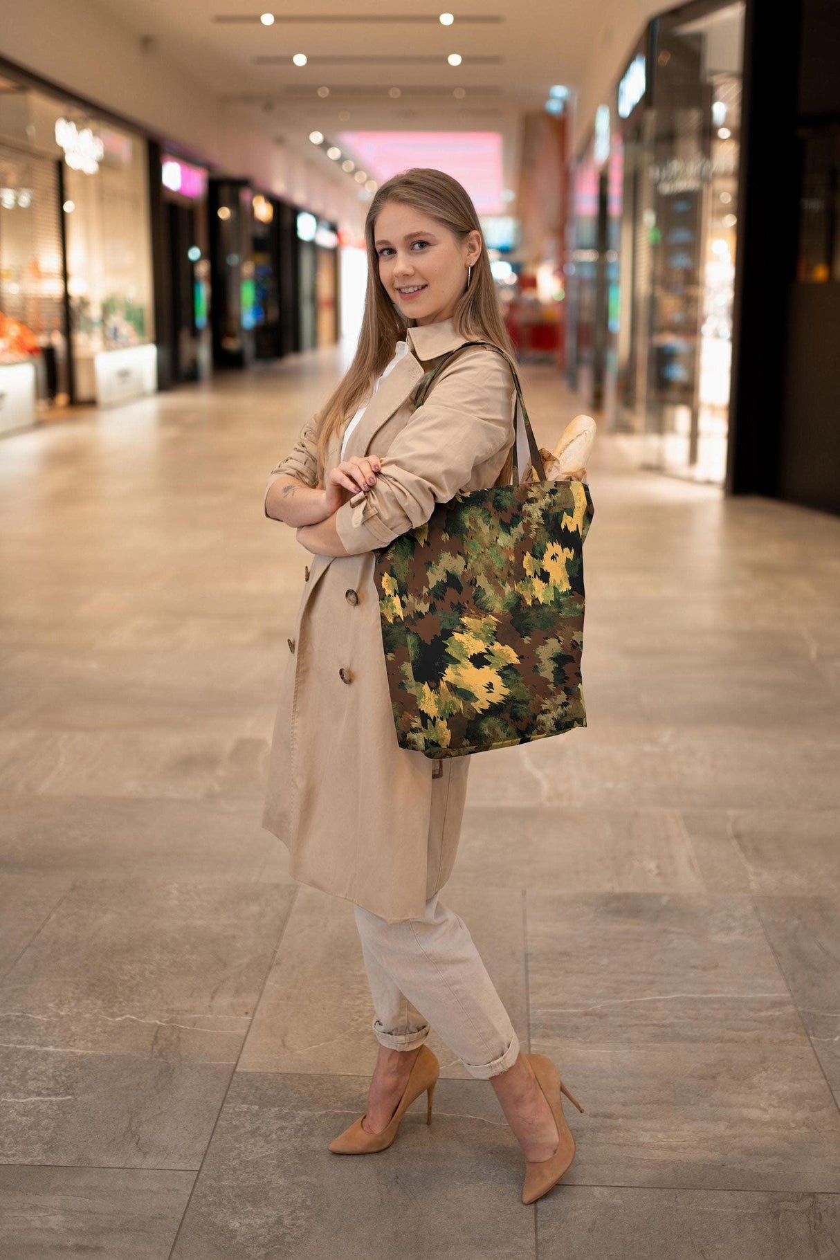Woman modeling a stylish military-patterned tote bag in a shopping mall, showcasing versatility and elegance.