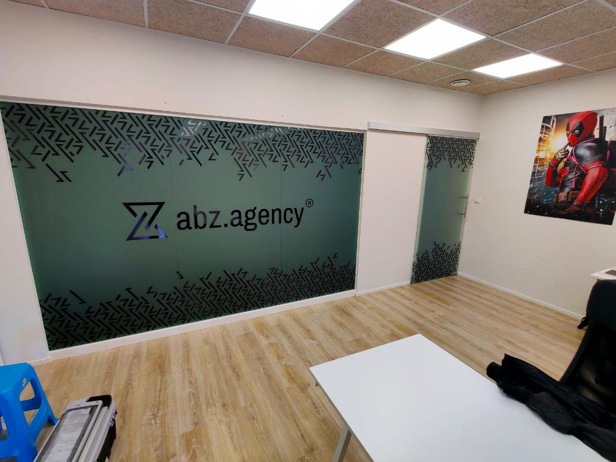 Office interior featuring custom frosted film decal with logo and decorative design on glass partitions.