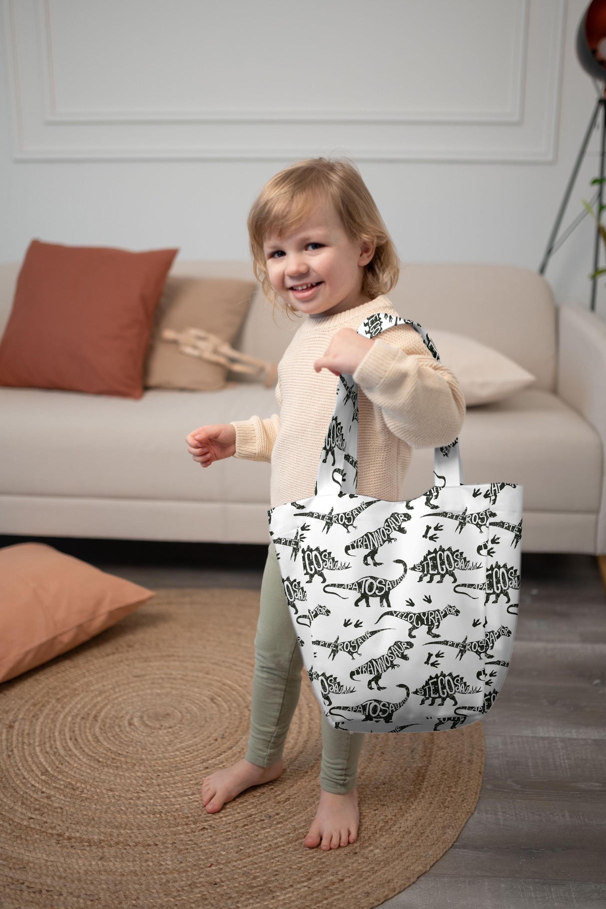Smiling child holding a cute dinosaur tote bag, showcasing its playful design and lightweight durability.