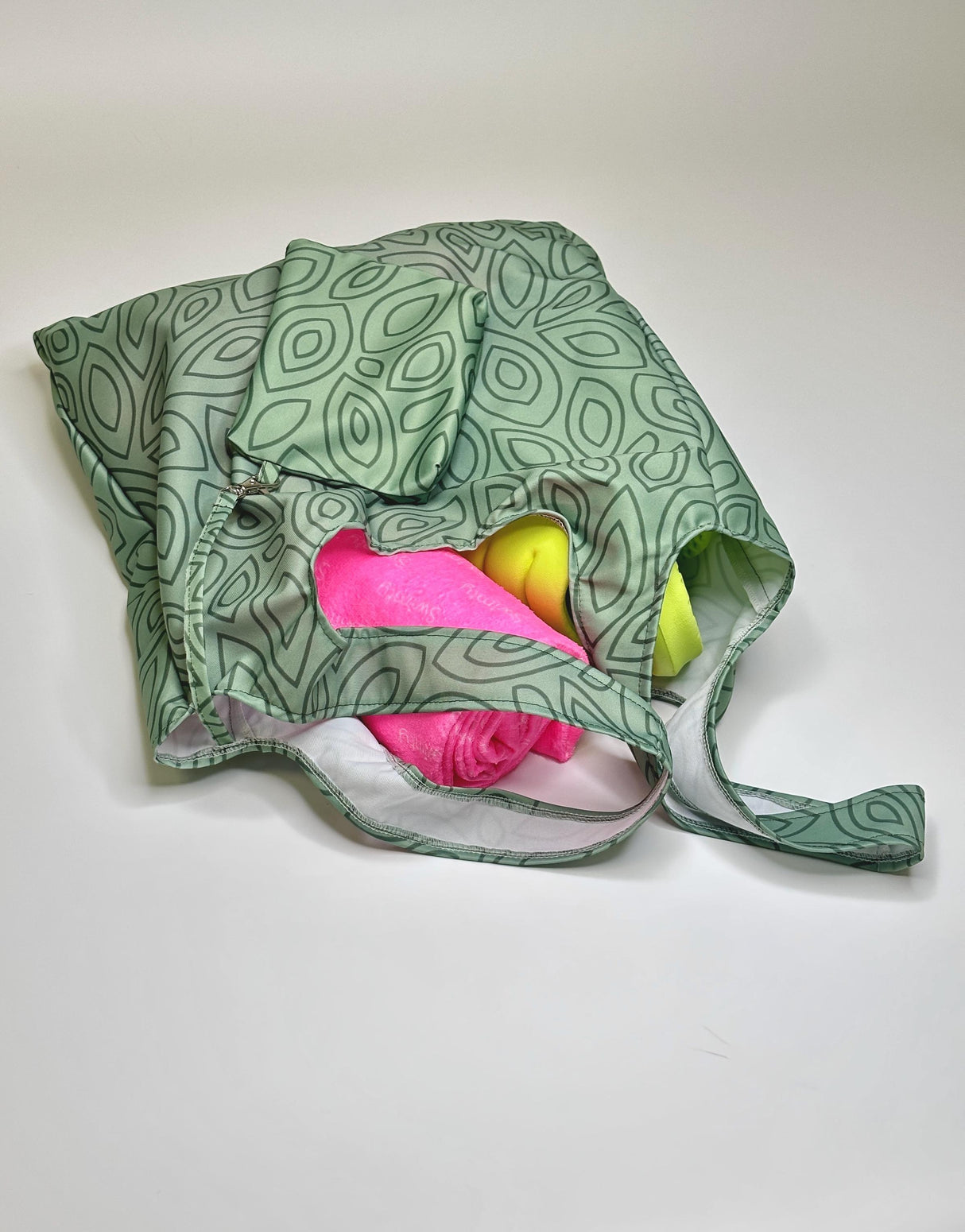 Women's XXL green leaves design shopper bag filled with colorful towels and accessories.
