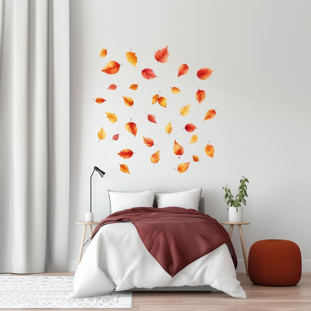 Set of 25 autumn leaves wall decals in warm colors above a bed, enhancing cozy fall decor.