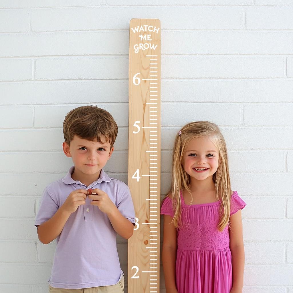 Two kids standing beside a wooden height ruler decal that says 'Watch Me Grow' for tracking height progression.