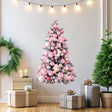 Pink Christmas tree wall decal decorated with cute ornaments in a festive room with gifts and lights.
