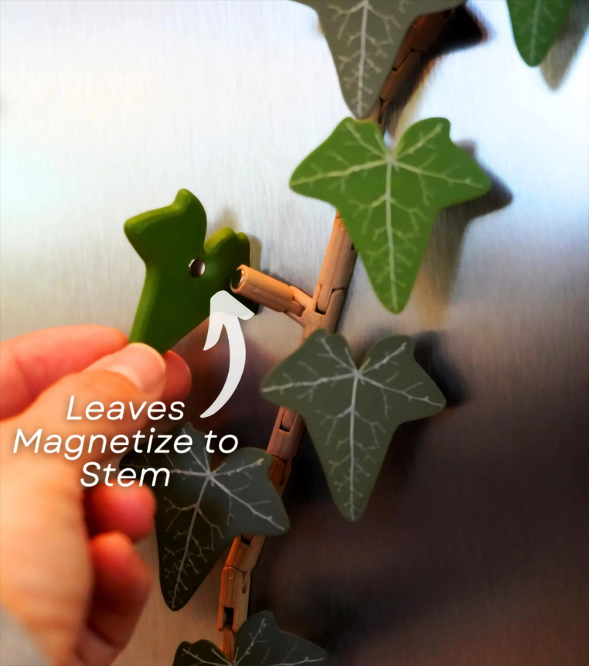 Hand attaching a leaf to the flexible stem of a custom color ivy fridge magnet.