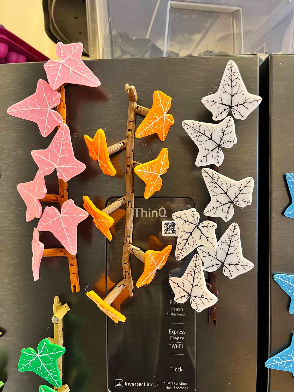 Colorful customizable ivy fridge magnets featuring pink, orange, and white leaves on a metallic fridge.