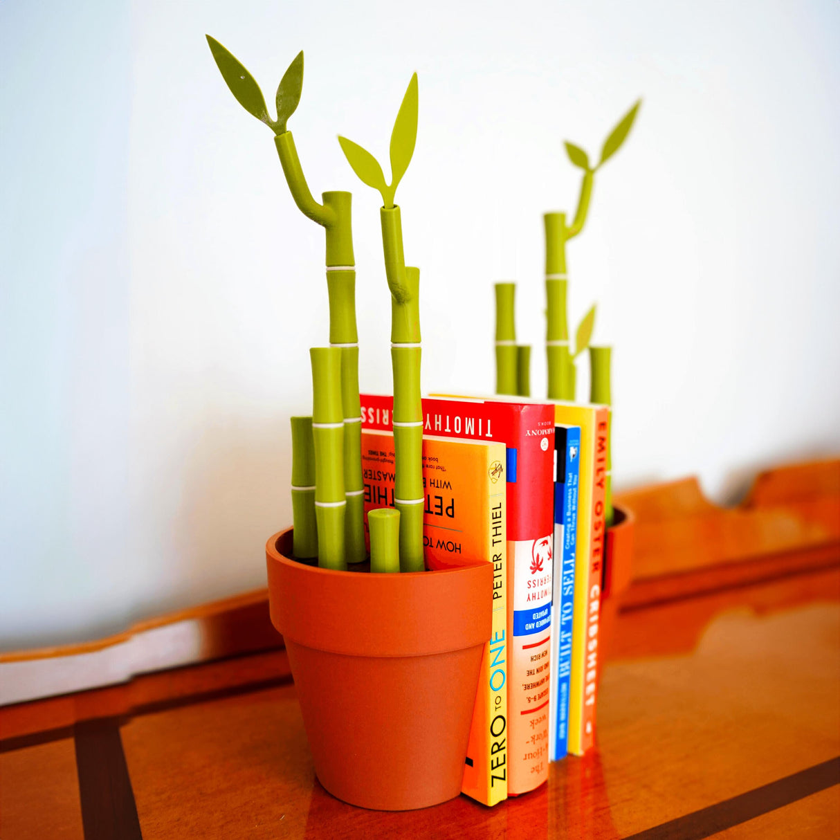 Bamboo bookends and pen holder with vibrant books on a desk, showcasing functional and stylish desk organization.