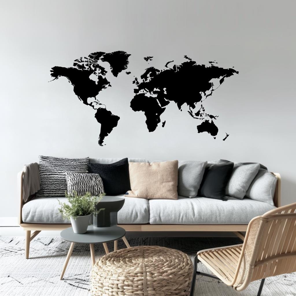 Modern black world map wall decal on living room wall above a stylish sofa with decorative pillows.