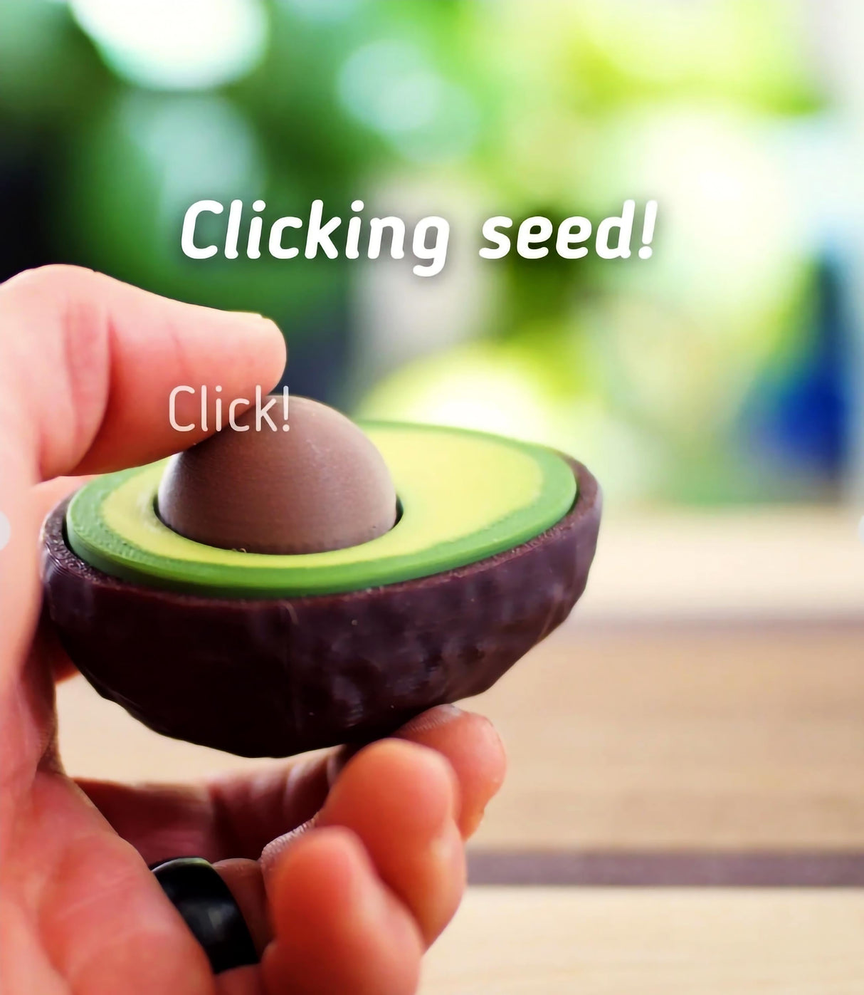 Hand holding an avocado clicker fidget toy, showcasing its clickable seed for stress relief and fun.