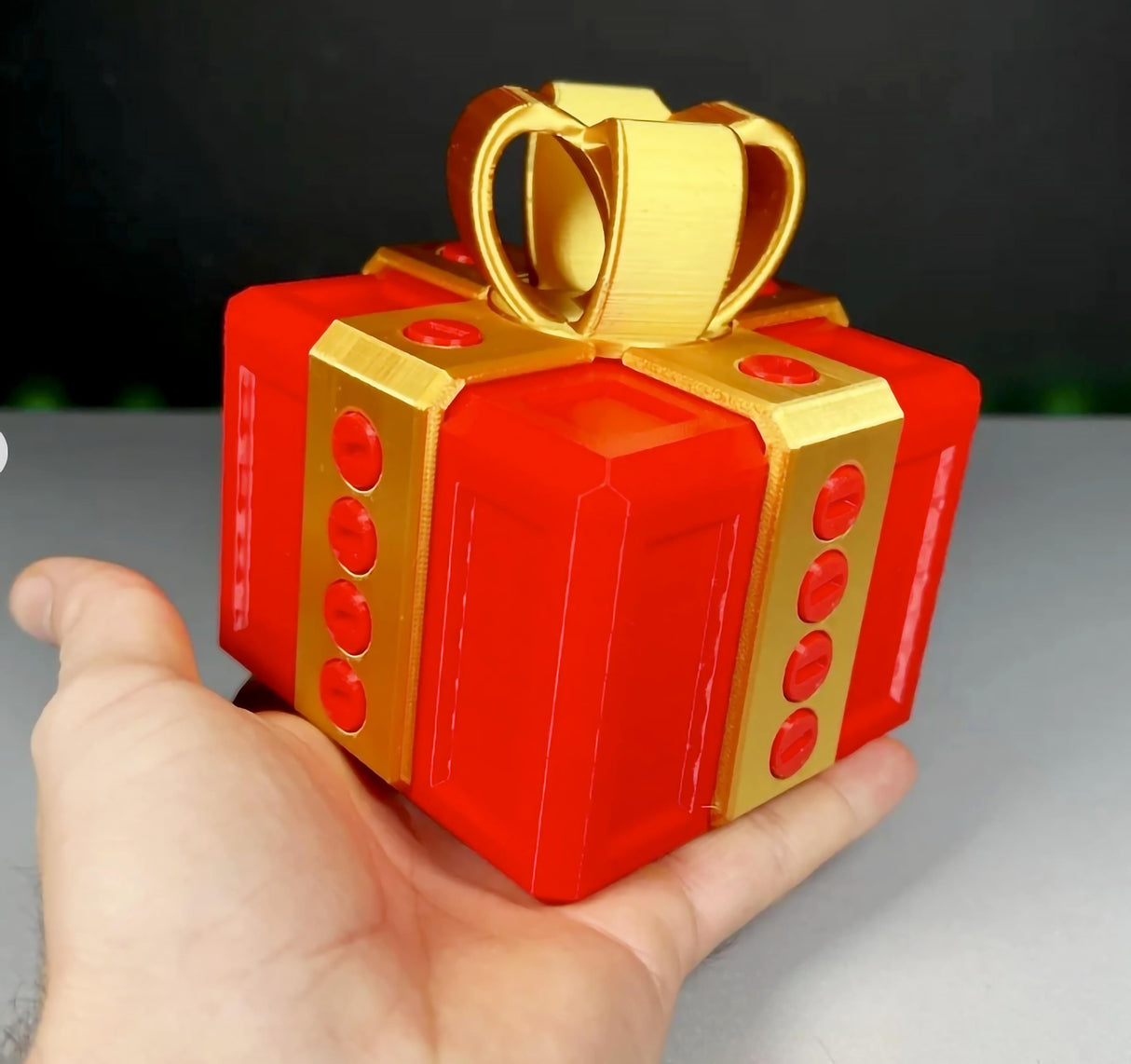 3D printed Annoying Gift Box with red and gold design, held in hand, perfect for pranks and fun challenges.
