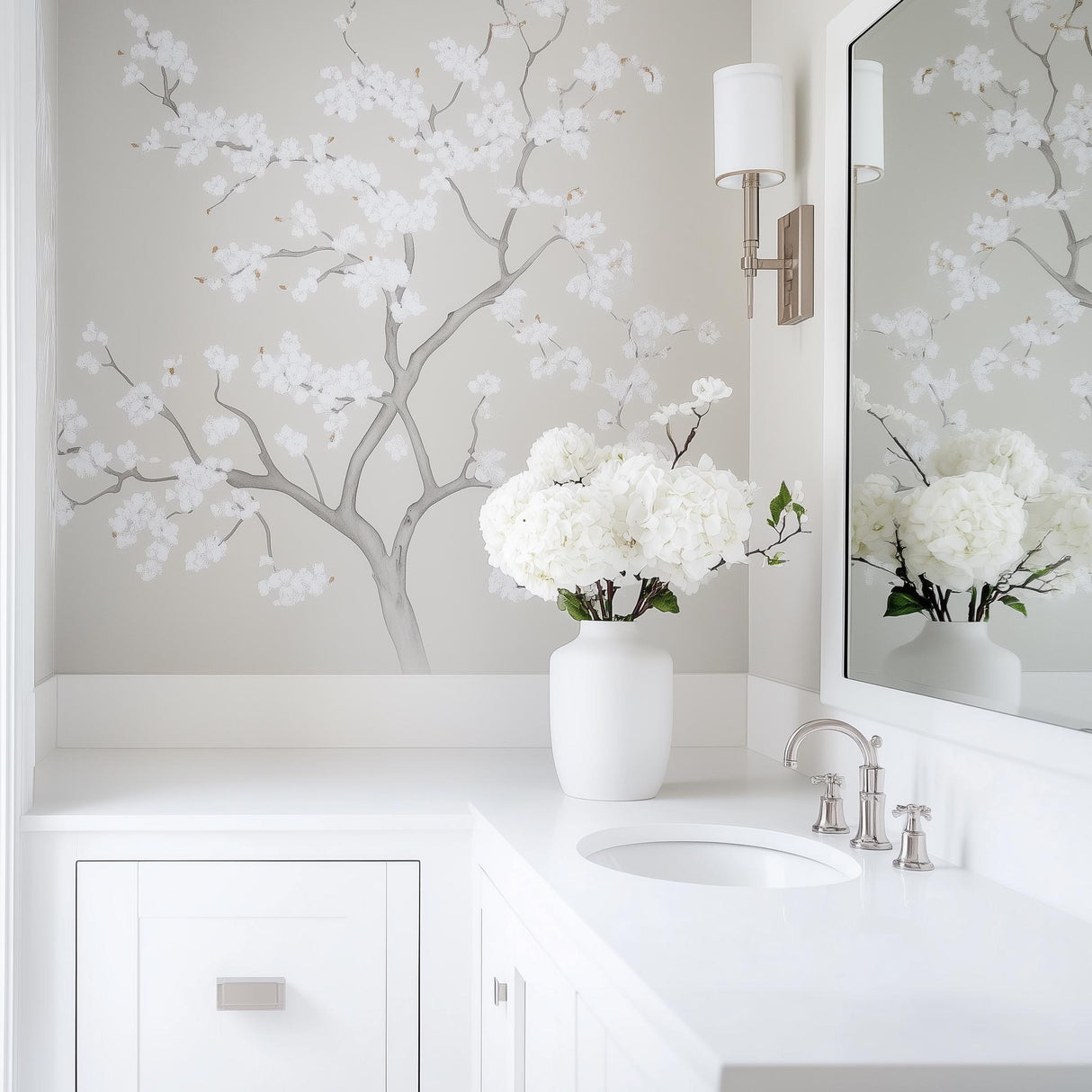 Chinoiserie tree wall decal with white flowers in a light gray bathroom, featuring a modern sink and vase of hydrangeas.
