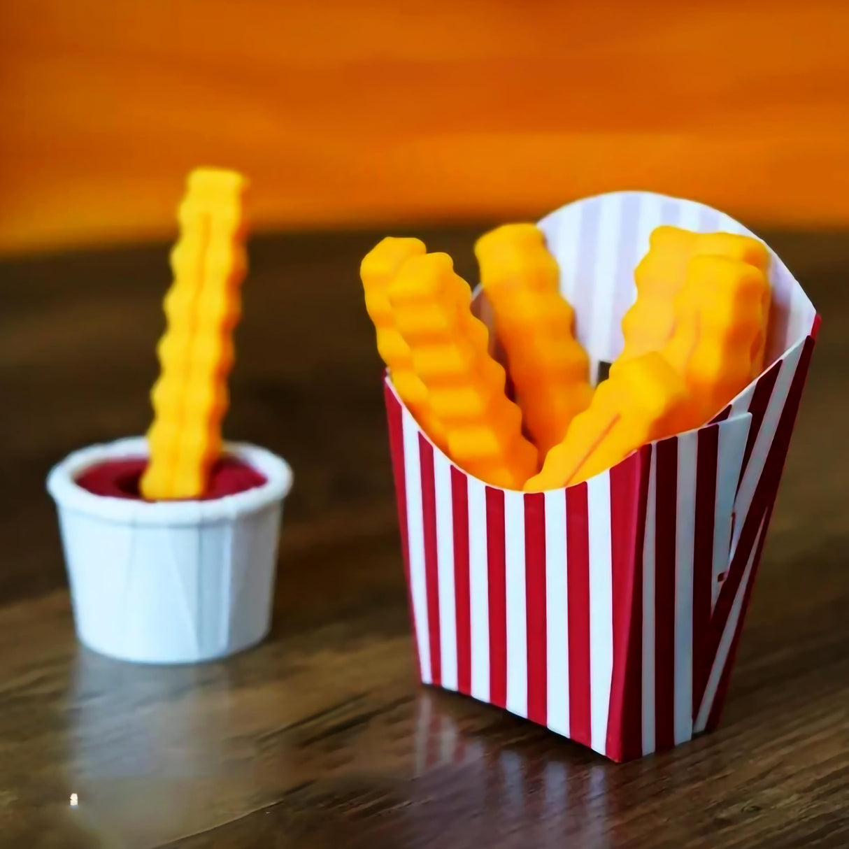 Colorful 3D-printed French fry clips in a fun striped container, perfect for sealing snack bags.