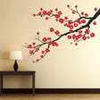 Plum blossom wall decal with red flowers and black branch on beige wall, enhancing Asian-inspired home decor.