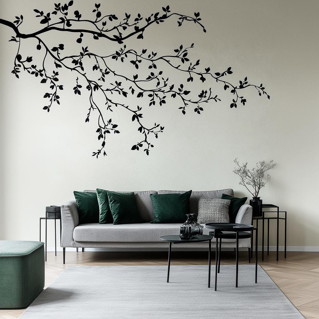 Minimalist black branch wall decal above a modern gray sofa with green cushions in contemporary living room.