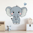 Cute cartoon elephant wall decal in a nursery setting, featuring pastel colors and a butterfly accent.