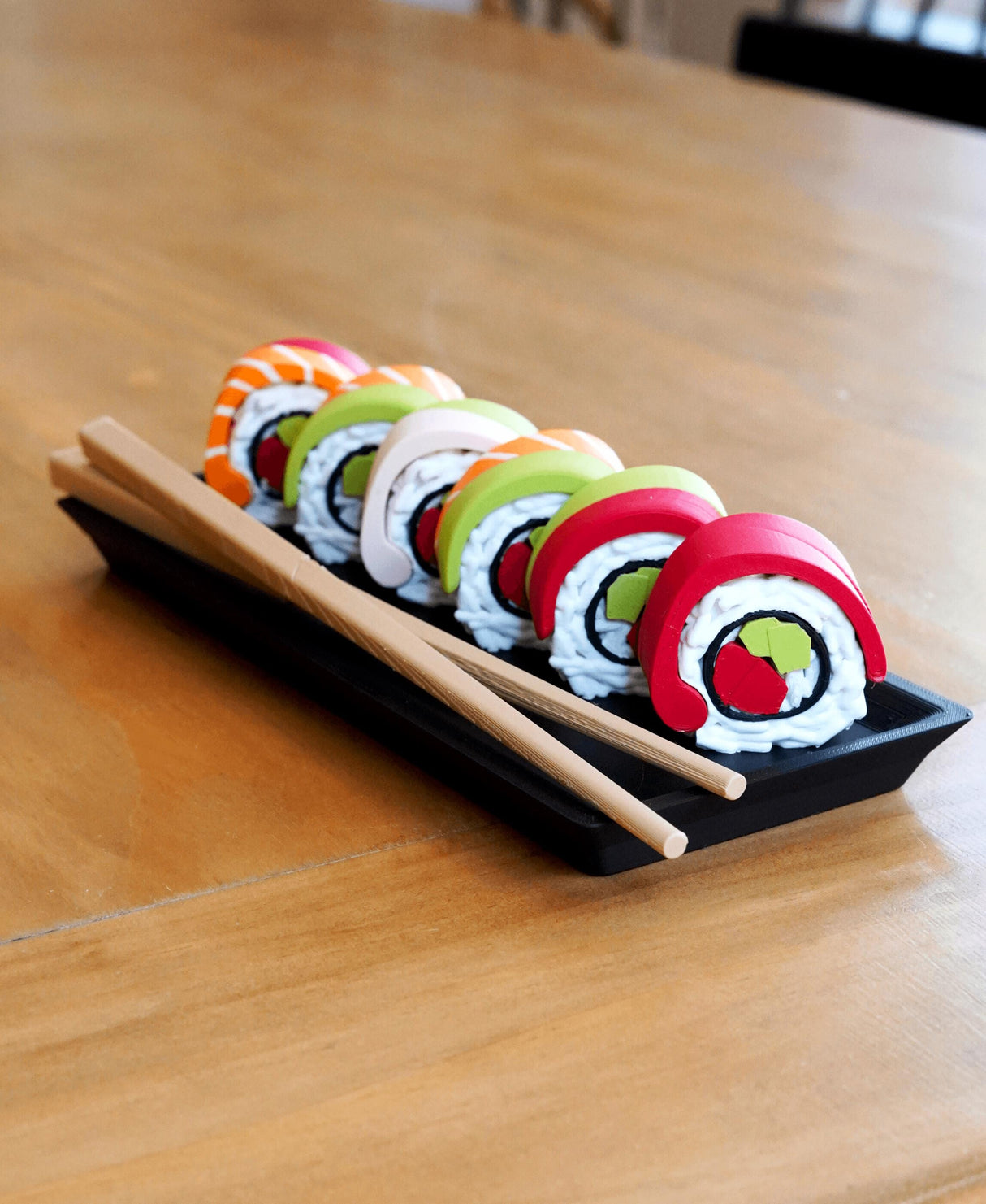 Colorful sushi-themed pill organizers in a tray with chopsticks, perfect for weekly supplements and a cute desk accessory.