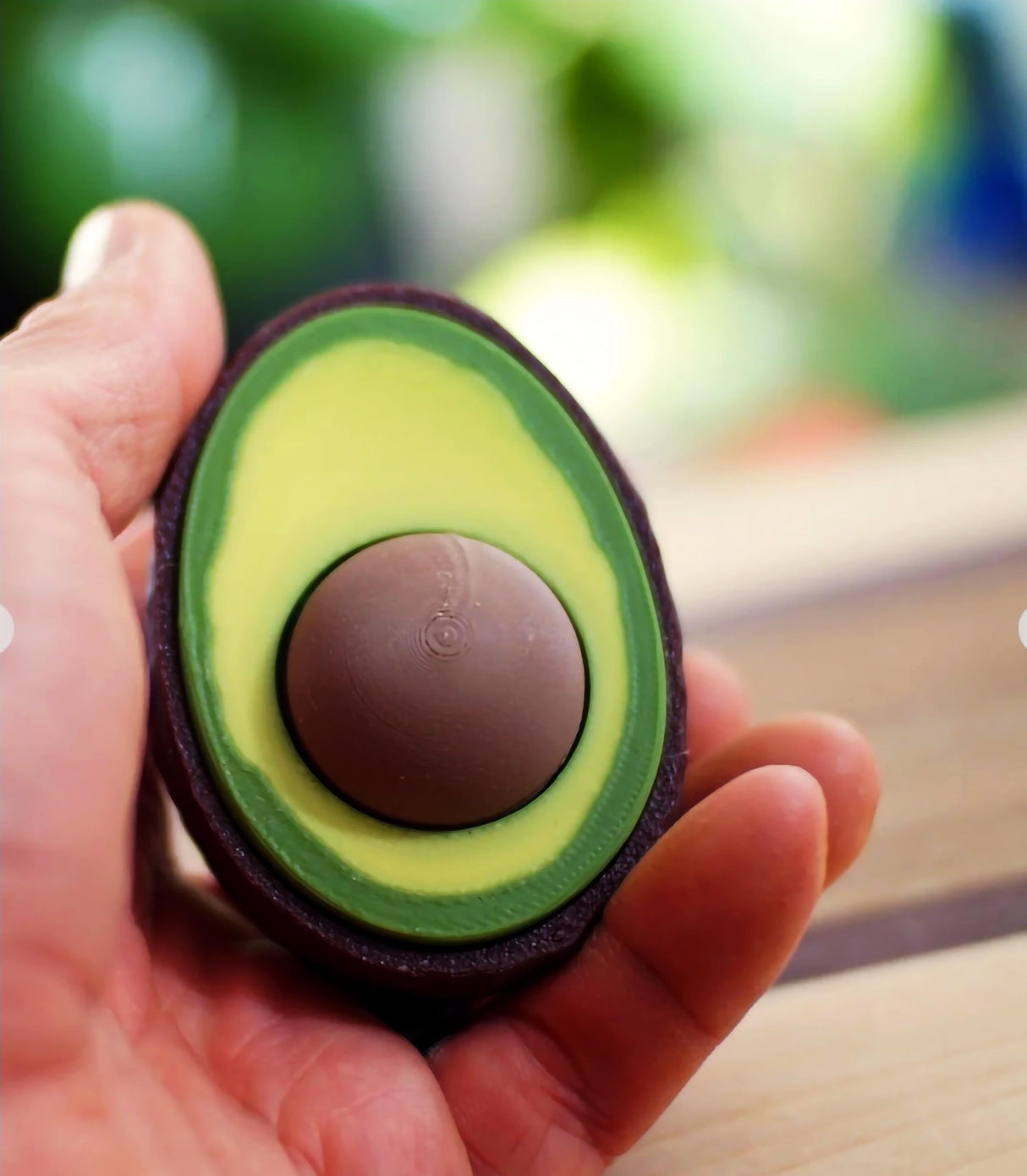 Avocado Clicker fidget toy in hand, featuring a clickable seed for stress relief and fun.