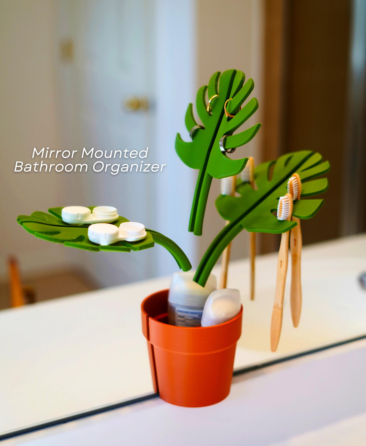 Mirror Monstera Organizer with green leaves for toothbrushes and soap, ideal for bathroom space saving and plant decor.