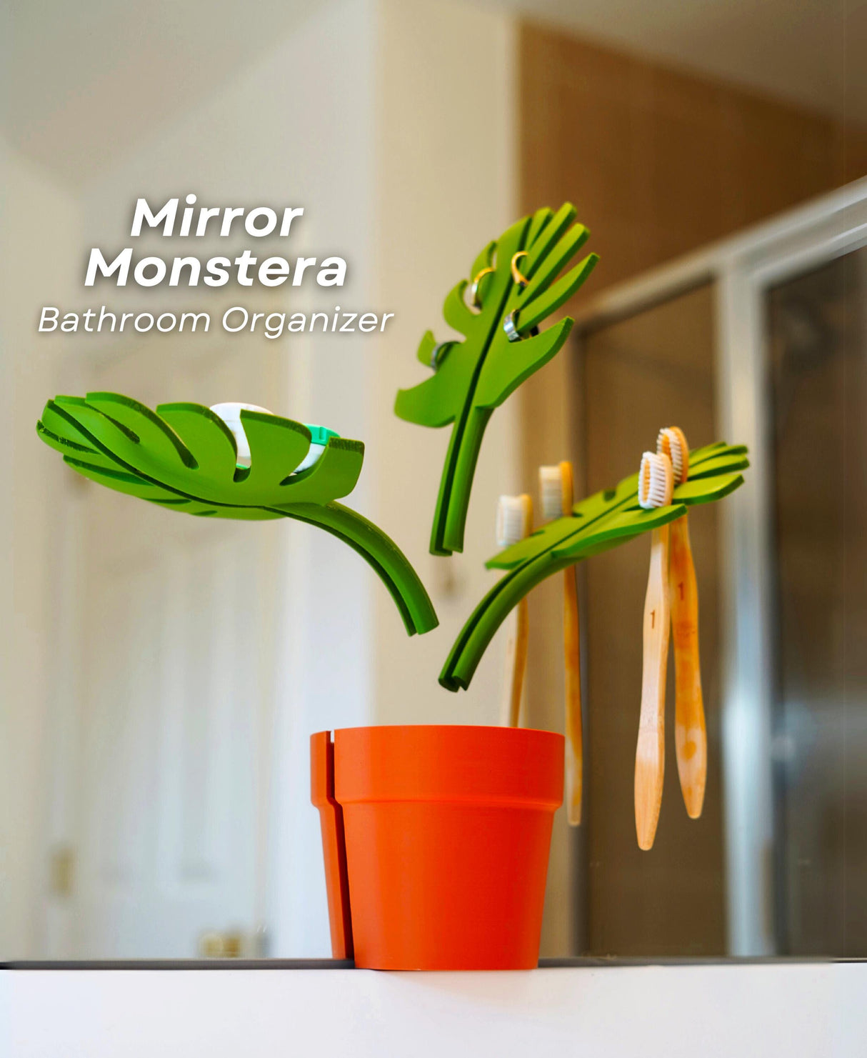 Mirror Monstera Organizer with green leaves holding toothbrushes in a stylish orange pot, ideal for bathroom storage.