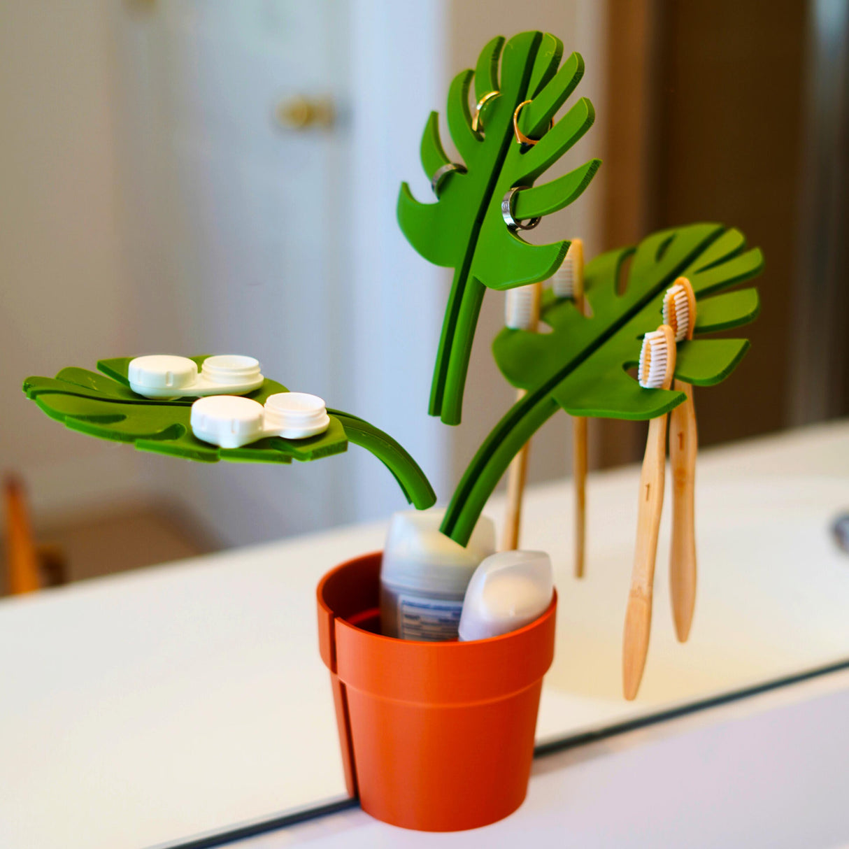 Mirror Monstera Organizer in a pot, featuring green leaves for storing toothbrushes and toiletries, adding charm to bathroom decor.