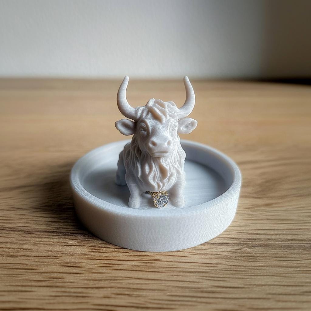 Adorable Highland cow jewelry dish, a 3D-printed ring holder on a rustic wooden surface.