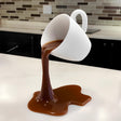 3D printed floating coffee cup sculpture pouring coffee in mid-air on kitchen counter