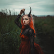 Model with red hair and gothic demon horns, wearing a black lace dress in a dark fantasy setting.