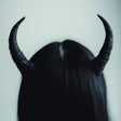 Small black demon horns on long dark hair, perfect for gothic cosplay and Halloween costumes.